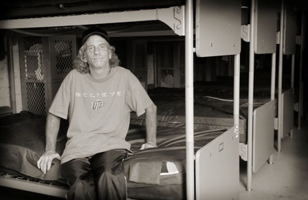 Homeless man sitting on his bunk at a shelter